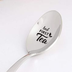 a spoon with the words but first tea on it is sitting on a white surface