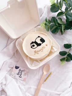 a cake in a box with a panda face on it next to a fork and plant