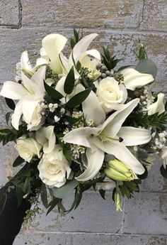 a bouquet of white flowers sitting on top of a brick wall