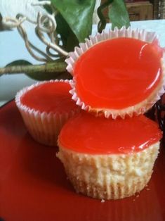 two cupcakes with red icing sitting on a plate