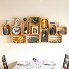 a dining room table with plates and vases on the wall above it, along with wooden crates