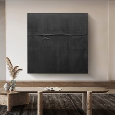 a large black painting hanging on the wall above a wooden bench in a living room