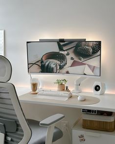 a desk with a monitor, keyboard and speakers on it in front of a white wall