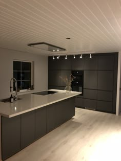 a large kitchen with an island counter top and lights on the ceiling over the sink