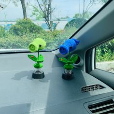 two crocheted flowers sitting on the dashboard of a car, one blue and one green