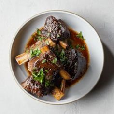 a white plate topped with meat covered in gravy and garnished with parsley