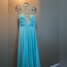 a light blue dress hanging on a hanger in front of a wall with a lamp