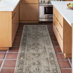 a kitchen with a rug on the floor next to an oven and sink in it