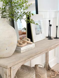 a white vase sitting on top of a wooden table next to two baskets filled with plants