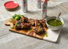 a wooden cutting board topped with meat and veggies next to cans of salsa