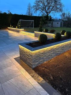 an outdoor garden area with lights on the side and plants growing out of it's planters