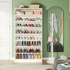 a white shoe rack filled with lots of pairs of shoes next to a green wall