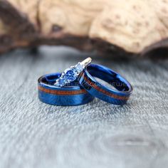 two wedding rings with blue and brown wood inlays are sitting next to each other