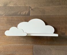 a white cloud shaped shelf sitting on top of a wooden floor next to a wall