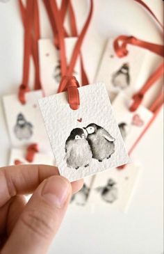 someone is holding up some small tags with birds on them and red string attached to the tags