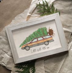 a painting of a car with a christmas tree on the hood is displayed in a white frame