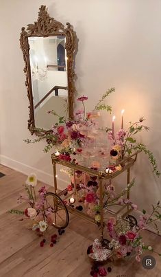 a table with flowers and candles on it in front of a mirror, next to a bicycle