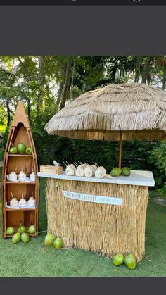 an outdoor bar set up in the grass with straw umbrellas and plates on it