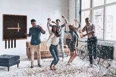 a group of people celebrating in a living room with confetti all over the floor