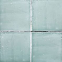 a white tile wall that has some water droplets on the tiles and one is green