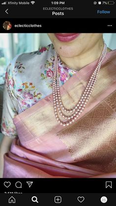 a woman wearing a pink and gold sari with pearls on her necklace, looking at the camera