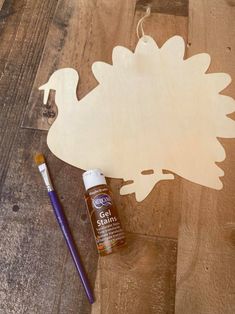 a wooden cutout of a hedge with paint next to it and a brush on the floor