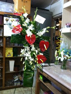 a vase filled with white and red flowers on top of a wooden table next to a book shelf