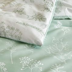 the bed is made with green and white floral designs on it's sheet set