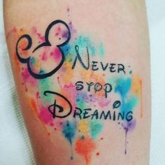 a colorful tattoo with the words never stop dreaming written in black ink on someone's leg