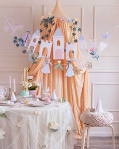 a table set up for a tea party with paper decorations and bunting around it