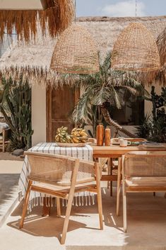 an outdoor dining area with straw umbrellas and wicker chairs, palm trees in the background