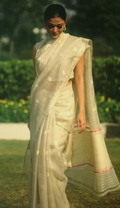 a woman in a white sari walking on grass