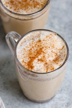 two mugs filled with coffee and topped with cinnamon sprinkled on the top