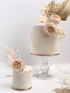 two wedding cakes decorated with flowers and feathers