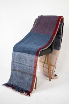 a blue and red blanket sitting on top of a wooden chair next to a white wall