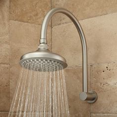 a shower head with water flowing from it's side in a tan tiled bathroom