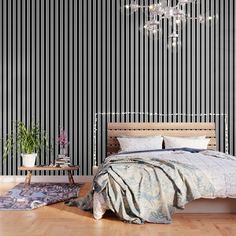 a bedroom with black and white striped wallpaper, wooden flooring and a chandelier