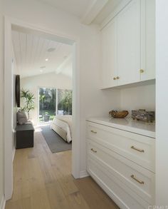 a bedroom with white walls and wood flooring next to an open door leading to a patio