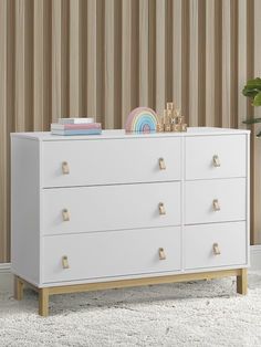 a white dresser sitting on top of a carpeted floor next to a potted plant