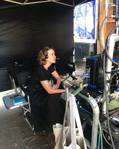 a woman sitting in front of a monitor on top of a desk with headphones