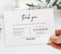 a person holding up a thank card with the words thank you on it in black ink