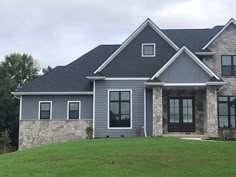 a gray house with black shutters on the front and side windows is shown in this image