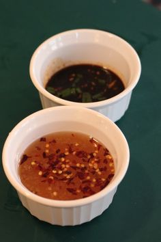 two white bowls filled with soup on top of a green table