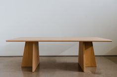 a wooden table sitting on top of a cement floor next to a white wall in an empty room