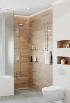 a white toilet sitting next to a walk in shower under a bathroom window with wooden paneling