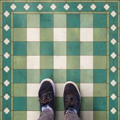 a person standing on a tiled floor with their feet up