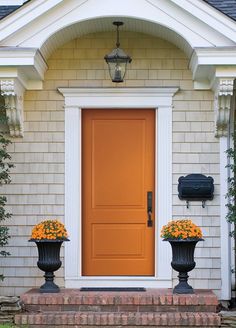 an orange front door with two black planters