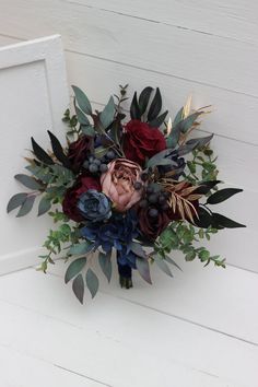 a bouquet of flowers sitting on top of a white wall next to a wooden door