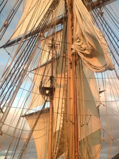 an old sailing ship with white sails on the water