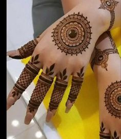 two hands with henna tattoos on them, one is showing off the intricate design